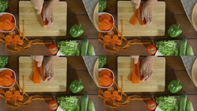 女酋长制作沙拉健康食品和在厨房切菜板上切碎胡萝卜的俯视图。