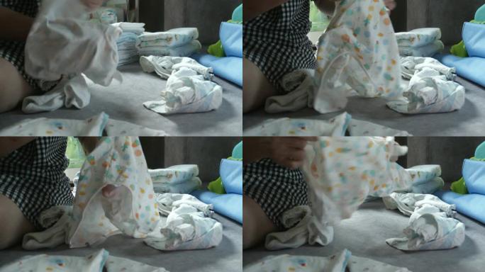妈妈在家手工折叠婴儿服装概念