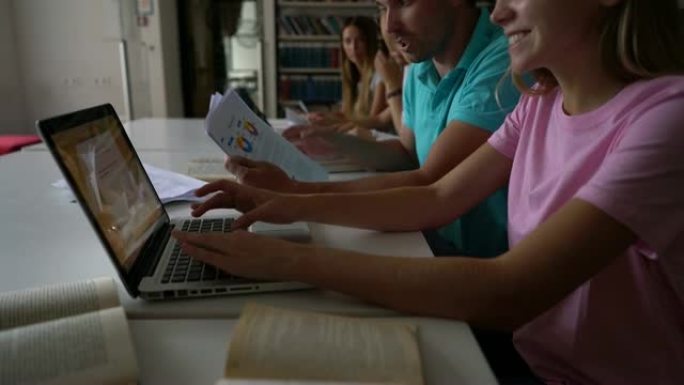 开朗的学生使用笔记本电脑，书籍和文档进行作业