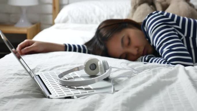 亚洲女性放松睡眠，用耳机听音乐