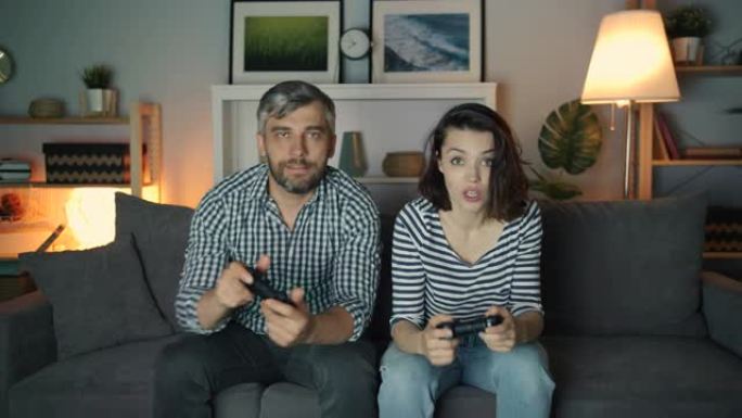 兴奋的男人和女人在黑暗的公寓里玩电子游戏