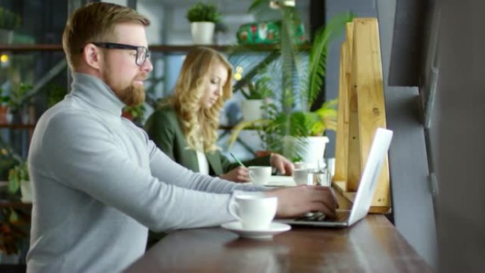 红发商人在笔记本电脑上工作，在咖啡馆喝咖啡