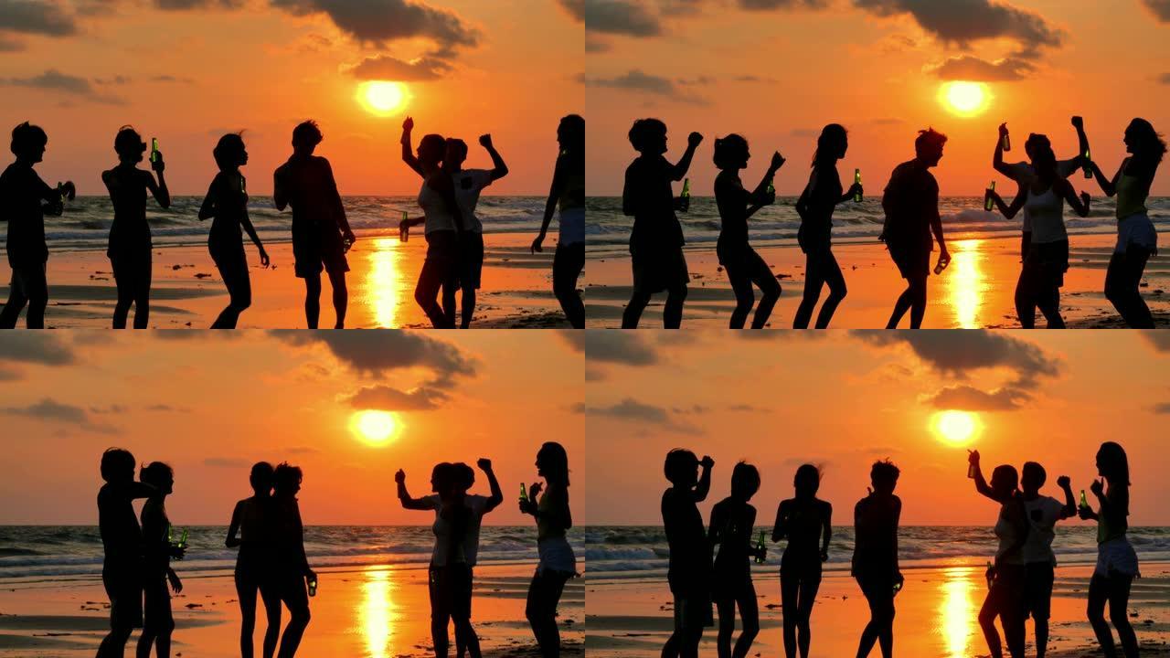 一群在海滩上玩耍和喝酒的朋友的剪影。假期-iStock