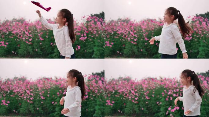 SLO MO可爱儿童女孩在美丽的花田玩玩具飞机
