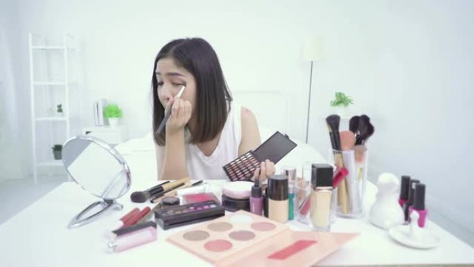 4k分辨率亚洲女性美容博主或v-logger在她的眼睛上涂抹口红眼影做化妆教程