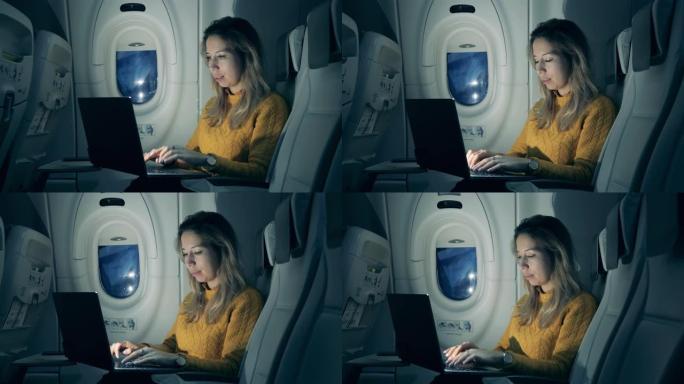 晚上的飞机机舱，一名妇女操作笔记本电脑