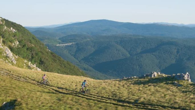 无人机: 运动的年轻夫妇沿着斯洛文尼亚风景秀丽的小路骑山地自行车。
