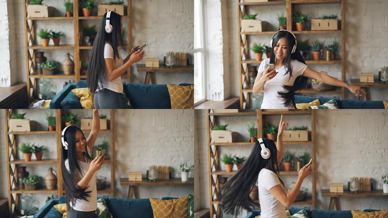 快乐的亚洲女学生的慢动作戴着耳机，拿着智能手机听音乐，跳舞，享受休闲时光。人和文化概念。