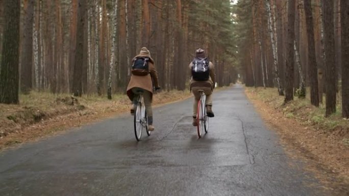 在令人讨厌的秋天，情侣骑着自行车穿过松树林