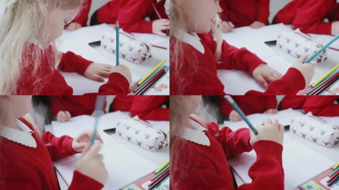 年轻的白人女学生在婴儿学校教室的桌子上画画，特写，过肩视图