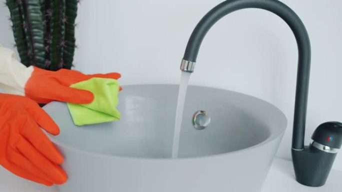 用湿布清洗浴室水槽的橡胶手套女性手的特写