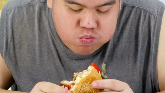 男人吃汉堡和饿男人吃的特写照片。真实的身体