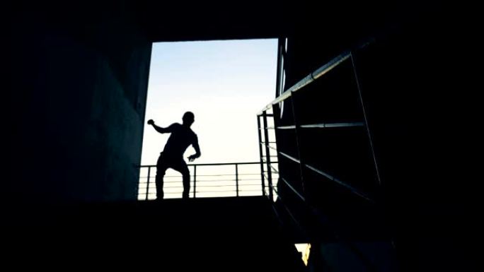 一个人在楼梯附近的滑板上跳跃，慢动作。