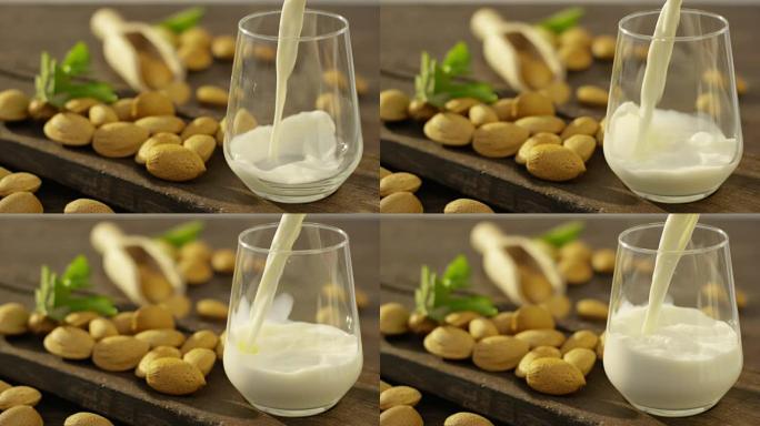 杏仁奶在慢动作倒入玻璃杯中，背景在树林中有杏仁，非常适合健康饮食的饮食，可以用作药物。