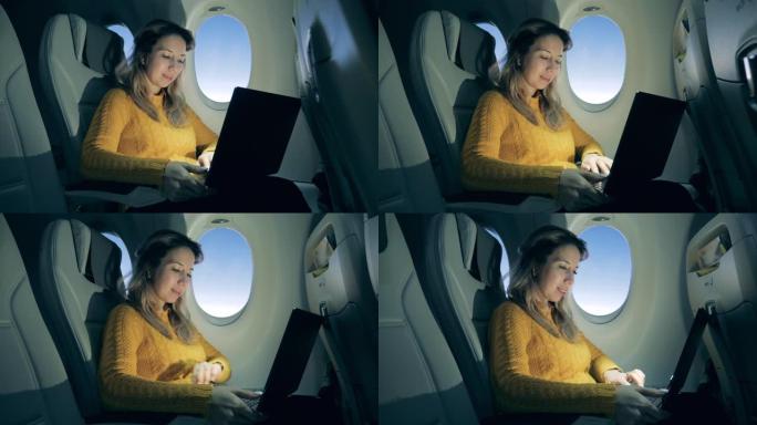 可爱的女人在日出时在飞机上的笔记本电脑上工作