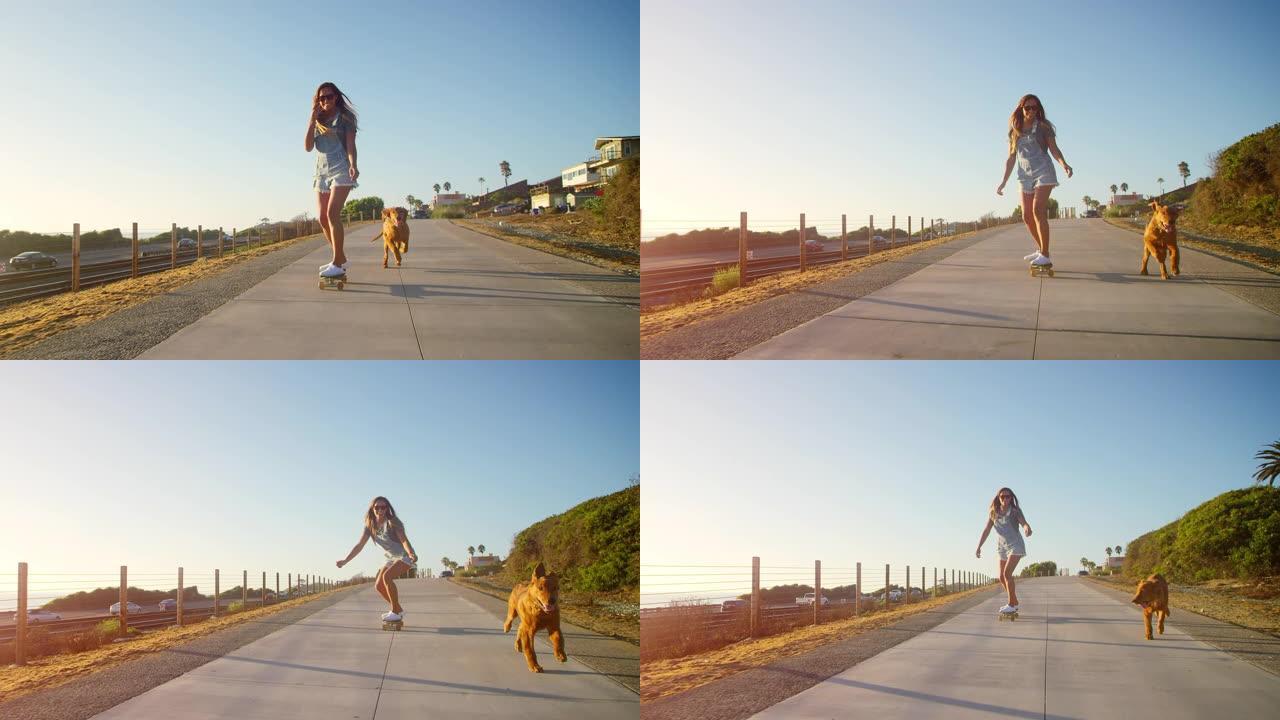 年轻快乐的微笑女孩在日落时与金毛猎犬小狗一起滑板