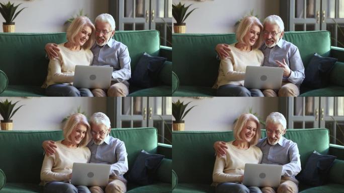 六十岁积极开朗的配偶坐在沙发上使用笔记本电脑