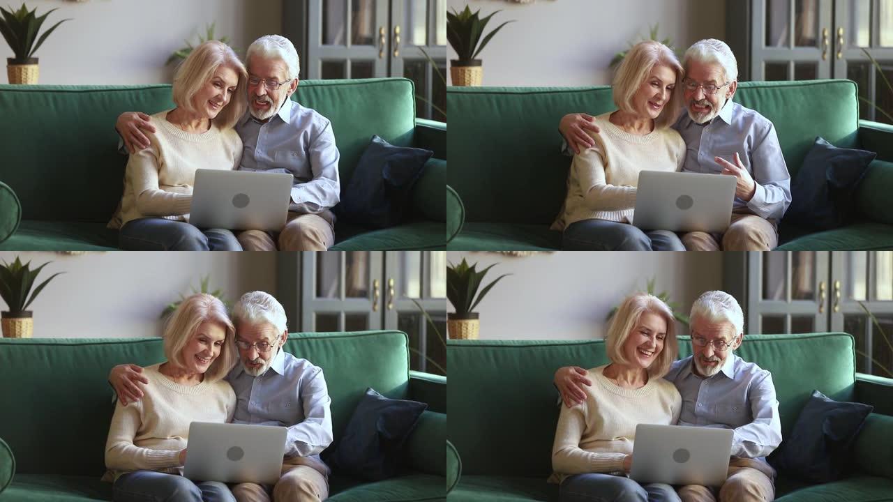 六十岁积极开朗的配偶坐在沙发上使用笔记本电脑