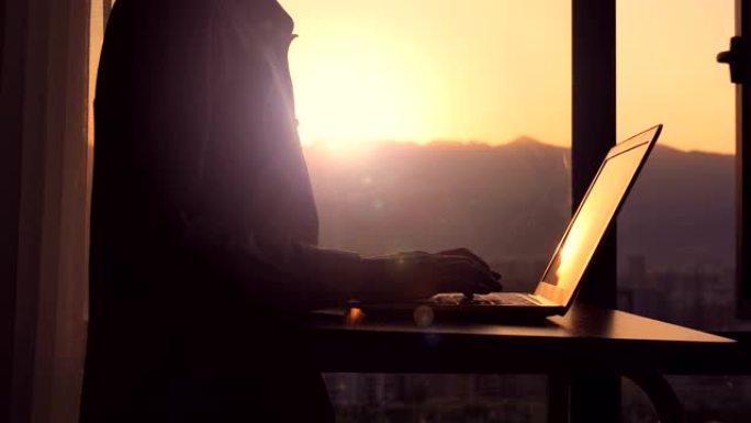 日落时在笔记本电脑上打字的特写男人