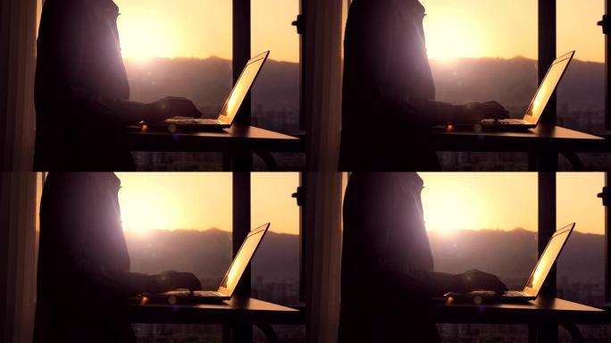 日落时在笔记本电脑上打字的特写男人