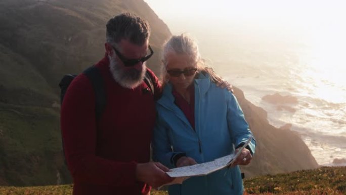 高级高加索夫妇在海边悬崖顶上查看地图