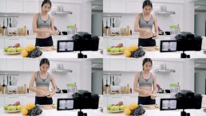 博主运动的亚洲女性使用相机录制如何制作鳄梨汁视频为她的订户，女性使用有机水果自己在家制作鳄梨汁。健康