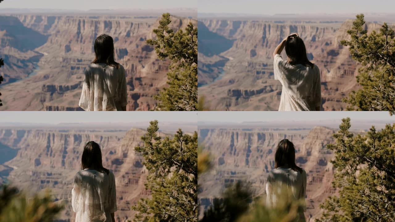 回顾年轻快乐的旅游女人抚摸头发，观看令人难以置信的大峡谷沙漠山脉风景。
