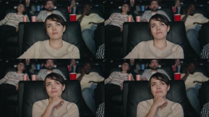 漂亮的女士坐在黑暗的大厅里在电影院看悲伤的电影情节剧