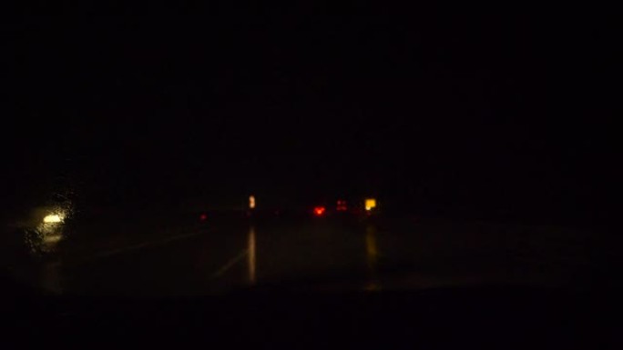 特写: 雨刷在雨夜沿着高速公路行驶时清洁挡风玻璃。