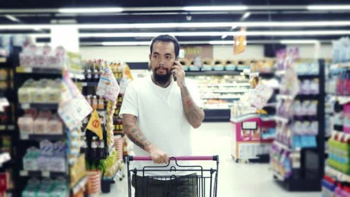 一名男子使用智能手机，走过商店的新鲜农产品区。
