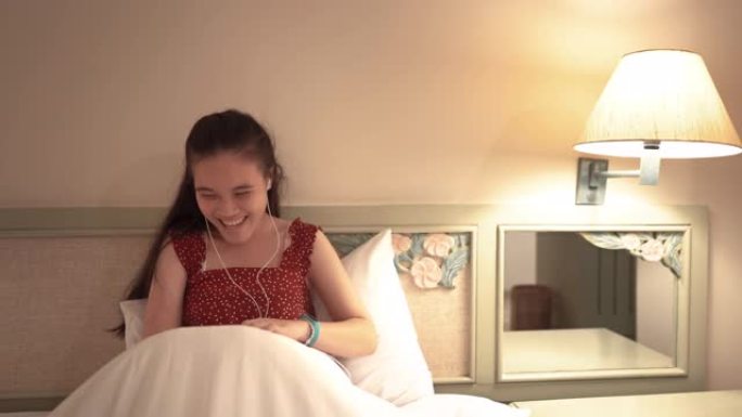 微笑的少女在卧室里看智能手机