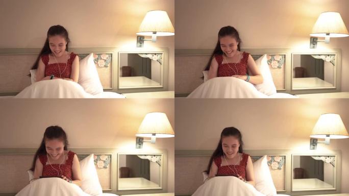 微笑的少女在卧室里看智能手机