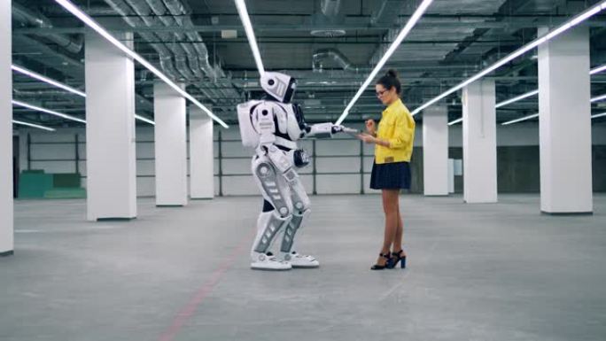 年轻女子使用平板电脑控制机器人。