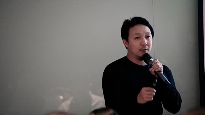 亚洲演讲者身着休闲装，4K慢镜头在会场前的舞台上，在会议厅或研讨会会议室展示商业和教育理念