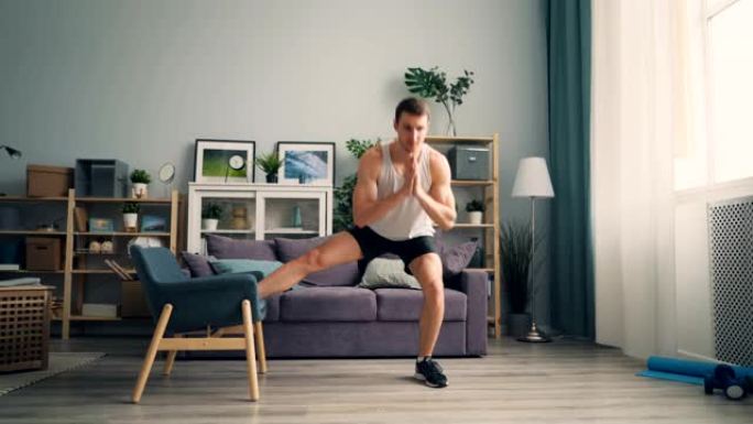 帅哥运动员在公寓里用扶手椅蹲坐，享受运动