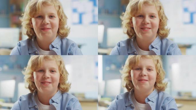 一个可爱的小男孩的肖像，一头金色的卷发坐在他的课桌前，开心地微笑着。聪明的小男孩，带着迷人的微笑坐在