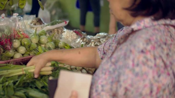 购买水果和蔬菜的资深亚洲妇女站在农贸市场