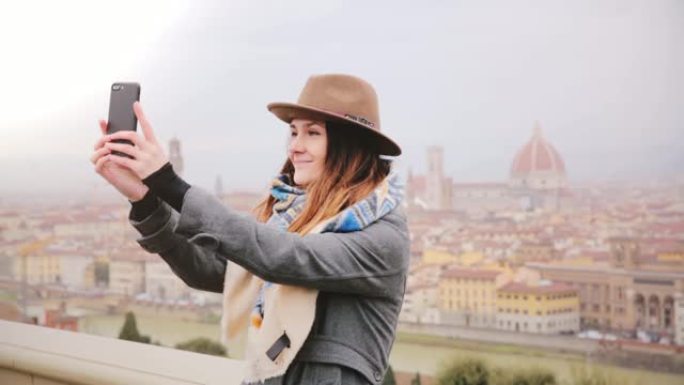 快乐微笑的旅游女孩在意大利秋天雾蒙蒙的佛罗伦萨惊人的城市景观全景拍摄智能手机自拍照片。