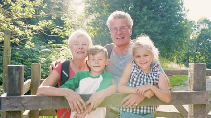 在英国湖区徒步旅行的祖父母和孙子孙女的慢动作肖像，看着木门