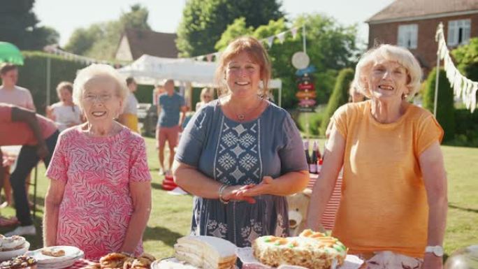 英国夏季花园宴会上在蛋糕摊上服务的三个成熟女性的肖像-慢动作拍摄