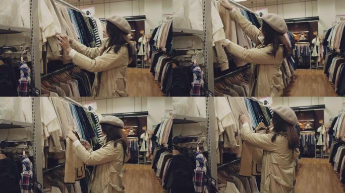 年轻的亚洲妇女在购物中心的架子上选择衣服