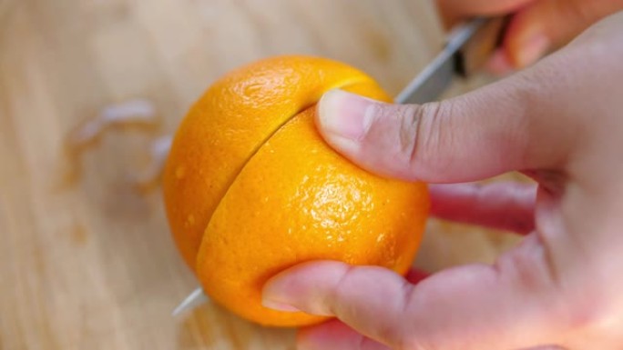 女人的手在橙色新鲜水果上切橙汁
