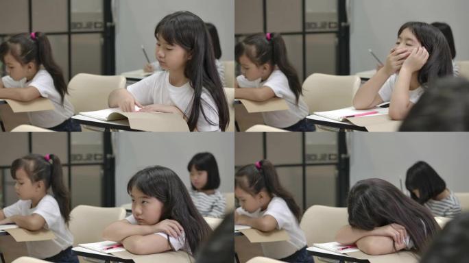 女孩因为学习太多而睡着了。睡在教室桌子上的亚洲女学生。