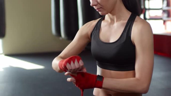 年轻的女拳击手在健身房用双手绑住