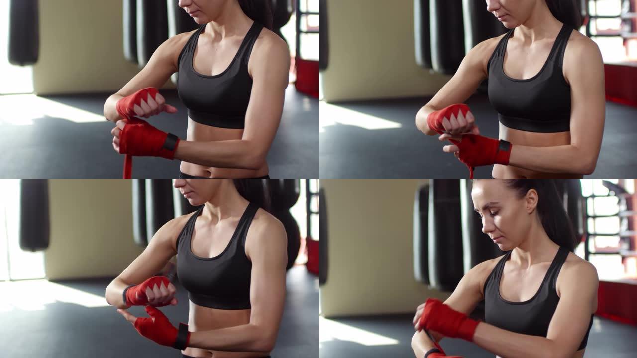 年轻的女拳击手在健身房用双手绑住