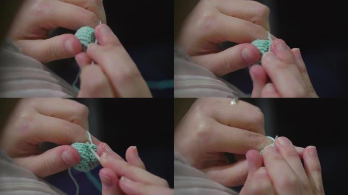 用线和钩针缝制女人的手的特写。