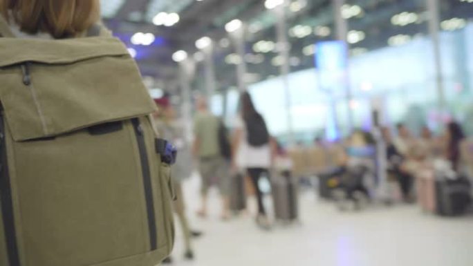 年轻的亚洲背包客女游客在国际机场登机口登机时走在航站楼大厅。生活方式背包旅游度假概念。