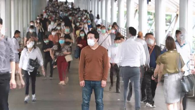 亚洲男子戴口罩防止冠状病毒或新型冠状病毒肺炎在拥挤的人群中爆发