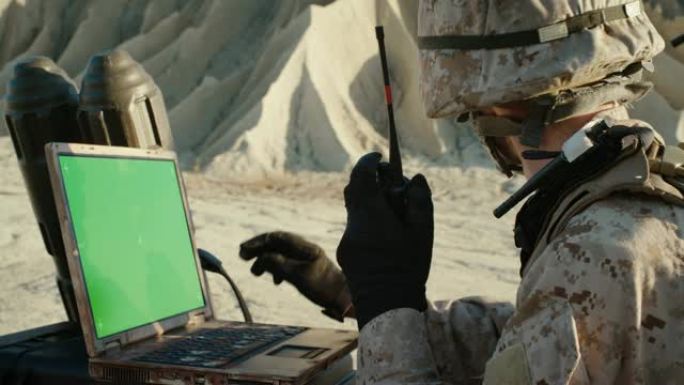 沙漠中的军事行动: 士兵在绿色乔马钥匙屏幕笔记本电脑上工作，使用无线电通信。
