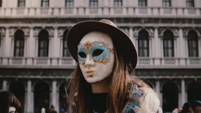 在威尼斯广场慢动作拍摄的戴着传统狂欢节面具的长发女游客的特写镜头。